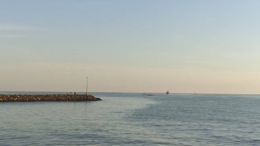 Limanın yakınındaki kumsala yerleştirilmiş büyük taş yığınlarından oluşan dalgalı istinat duvarı