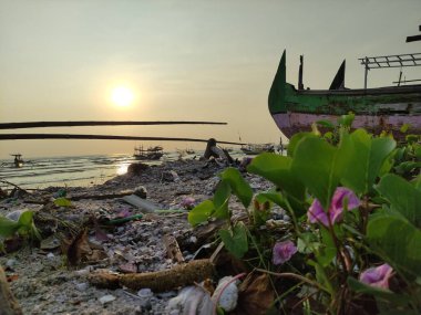 Gün batımında sahile demir atmış bir geminin silueti.