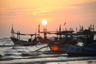 Gün batımında sahile demir atmış ahşap bir gemi.
