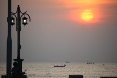 Denizde bir teknenin silueti Sabah kızıl güneşin arkasında