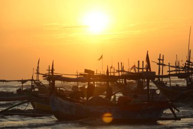 Gün batımında sahile demir atmış ahşap bir gemi.