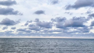 yumuşak deniz dalgaları ve beyaz bulutlarla dolu mavi bir gökyüzü