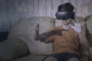 Asyalı çocuk fütüristik yaşam tarzı öğrenimi ve insan yolu simülasyon bilimleri üzerine VR gözlüğü takıyor. Gelecekteki teknoloji konsepti.