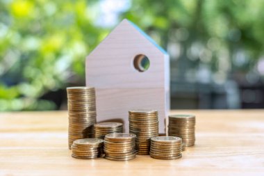 Paralar ahşap evin önüne istiflenir, para tasarrufu konsepti, emlak yatırımı, ev kredisi, ters ipotek, altın sikkeler para yığını büyümesi, para biriktirme yığını ev için gelecek istifleme