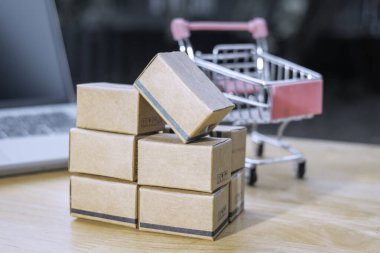 İnternetten alışveriş veya ecommerce ve dağıtım hizmeti konsepti için dizüstü bilgisayarında alışveriş kartı logosu olan kağıt kutular veya paket. İnternet üzerinden alışveriş hizmeti sunar ve internet üzerinden eve teslimat sunar.
