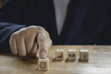 İş adamı, ticari strateji ve eylem planı olan tahta blokları seçmek için parmağını kullanır. İş geliştirme kavramını hedef alır. Duygu ve zihniyet kavramı.