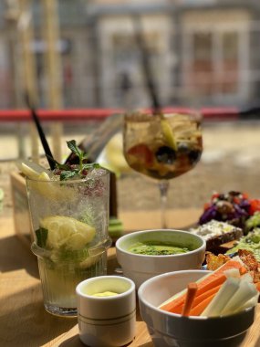 Pescara 'daki İtalyan açık hava aperatifi sırasında taze sebzelere ve kırsal ahşap yüzeydeki suya eşlik eden canlı kokteyller.