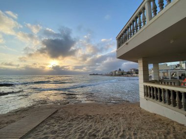Beyaz mimariyi aydınlatan altın gün batımı Santa Croce Kamerası 'nın kumlu kıyı şeridi Sicilya, Akdeniz manzarası