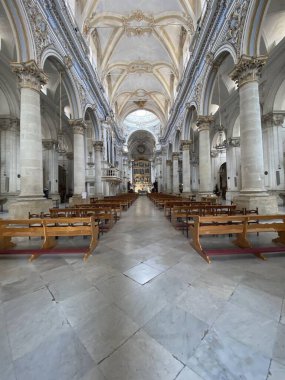 Modica, Sicilya 'da bir barok kilisesi olan Chiesa di San Pietro' nun etkileyici iç mekanının geniş açılı görüntüsü mermer zemini ve ahşap sıraları aydınlatıyor.