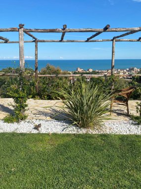 Roseto degli Abruzzi, Abruzzo, İtalya 'daki Adriyatik kıyısına bakan ahşap pergola manzaralı bir bahçe.