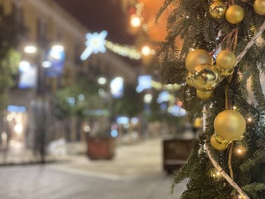 Pescara, İtalya 'da arka planda bulanık Corso Umberto I alışveriş caddesi ile süslenmiş bir çelenk ve altın Noel süsleri.