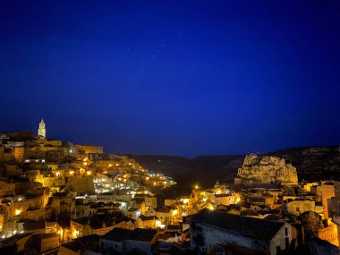 Matera 'nın gece parlayan manzarası yıldızlı gökyüzünün altında, Ursa Büyük takımyıldızı tarihi İtalyan şehrinin antik taş evlerini aydınlatıyor.
