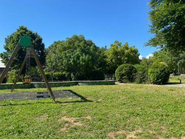 Pescara, Abruzzo, İtalya 'da güneşli bir yaz gününde, çocuk parkında yeşil bir oyuncak ayı süslemesi ile bebek salıncakları.