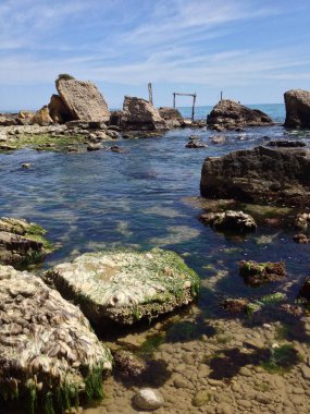 Antik bina kalıntıları yakınlarındaki kayalık kıyı şeridini kaplayan hafif dalgalar Ortona, Abruzzo, İtalya 'nın kristal berrak sularındaki yıpranmış taş yüzeyleri ortaya çıkarıyor.