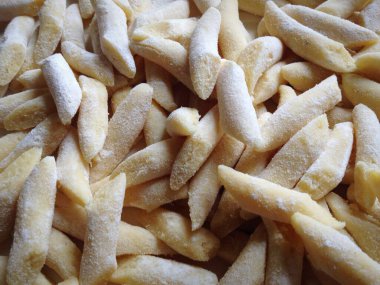 Taze Maccheroni alla Chitarra makarnası ahşap yüzeye serpilmiş, hafif un serpiştirilmiş, geleneksel Abruzzo mutfak sanatını sergiliyor.