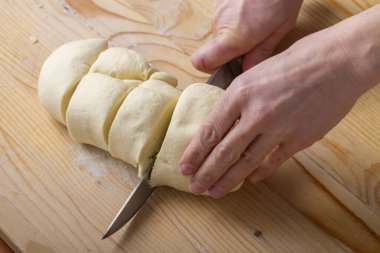 Kaba ahşap yüzeyde hamur doğramada usta fırıncı, aşçılık hazırlıkları için tek parça hamur işleri yapıyor.