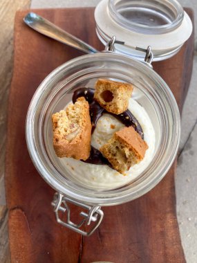 İtalyan, Toskana 'da tahta tahtada servis edilen kantuccini bisküvileri ve çikolata soslu kremalı küçük cam kavanoz.