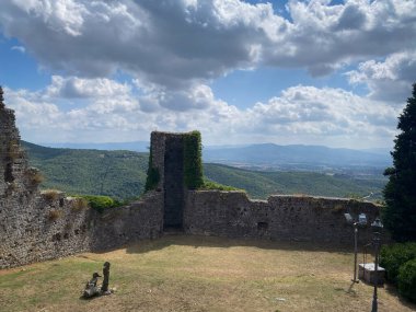 Tepeye tünemiş ortaçağ taş kaleleri, Val di Chiana 'daki tarihi Civitella' nın üzerinde bulutlu yaz gökyüzü ile panoramik Toskana manzarasını gözler önüne seriyor.