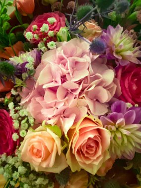 Güller, ortancalar ve diğer çiçekler de dahil olmak üzere canlı bir buket çiçek neşeli ve kutlama düzenlemesi oluşturur.