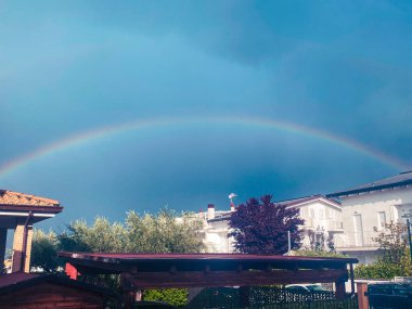 Renkli gökkuşağı Pineto, Abruzzo 'daki konut binalarının üstündeki gökyüzünü süslüyor, doğanın güzelliğini nefes kesici bir şekilde gösteriyor.