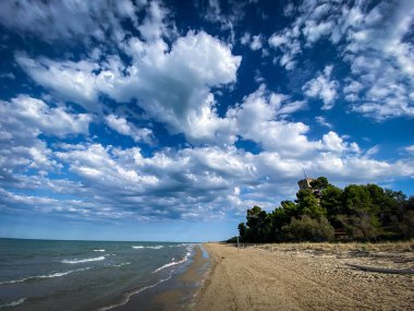 İtalya 'nın Abruzzo kentindeki Pineto kumsalına bakan tarihi sahil kulesi Torre del Cerrano' nun manzarası dinamik bulutlu bir gökyüzü altında.