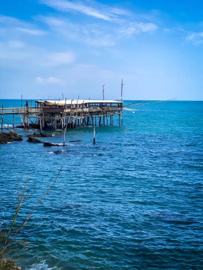 Abruzzo 'lu geleneksel bir balıkçı makinesi olan Punta Tufano' nun ahşap damıtma evi Rocca San Giovanni, İtalya 'da mavi Adriyatik Denizi' ne bakan güneşli bir gökyüzünün altında.