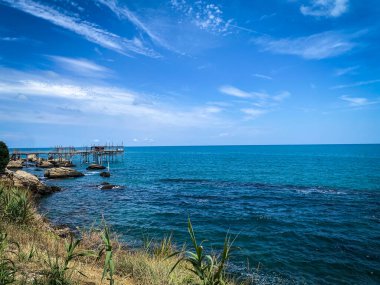 Güneşli mavi gökyüzünün altında, Abruzzo kıyılarının tipik bir balık tutma makinesi olan trabocco ile gösterişli deniz manzarası