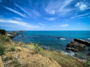 Trabocchi Sahili 'nin çarpıcı manzarası, İtalya' nın Abruzzo kentindeki güzel bir kıyı şeridi, trabocchi olarak bilinen geleneksel balıkçılık platformları, turkuaz sular ve berrak mavi bir gökyüzü.