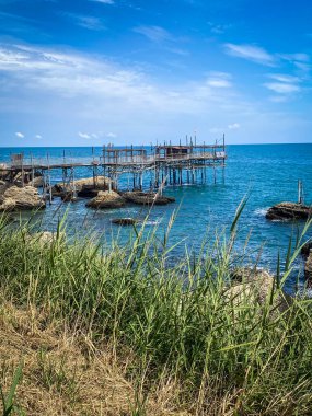 Geleneksel bir balıkçılık platformu olan Trabocco, İtalya 'nın Rocca San Giovanni kentindeki Adriyatik kıyısında mavi deniz ve gökyüzünün zeminine karşı duruyor.