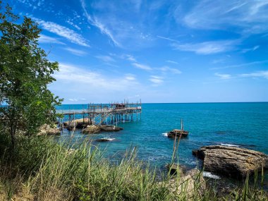 İtalyan Rocca San Giovanni, Abruzzo, İtalya 'nın Adriyatik kıyısında canlı mavi bir yaz gökyüzünün altında geleneksel bir balıkçılık platformu olan trabocco manzarası