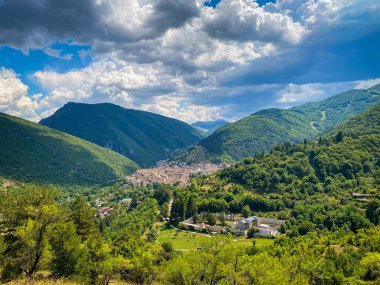 Scanno 'nun panoramik manzarası, İtalya, Abruzzo' da büyüleyici bir köy, yemyeşil dağlar ve dramatik bulutlu gökyüzü ile çevrili.