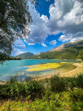 Arka planda dağlarla birlikte Scanno Gölü 'nün nefes kesici manzarası, İtalya' nın Abruzzo kentindeki bir yaz gününde bulutları yansıtıyor.