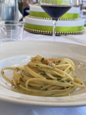 Deniz ürünleri spagettisi, deniz tarağı ve kızarmış ekmek kırıntıları. Beyaz bir tabakta taze maydanozla süslenmiş. İtalya 'da ana yemek olarak servis ediliyor.