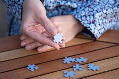 Kadının elinde yapboz parçaları var. İş kararları, başarı ve strateji kavramı. Ev yapbozu oyunu