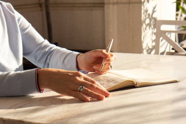 Güneş gören parlak bir masaüstüne dizüstü bilgisayara yazı yazan şık bir kadın. Kadın evdeki bir deftere not alıyor. Serbest çalışma, psikoloji, düşünür, eğitim kavramı