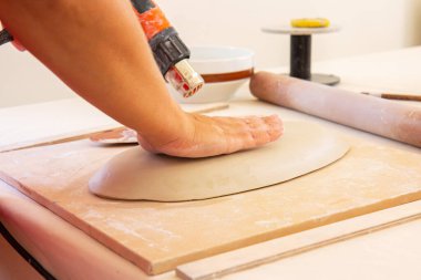 Kadın çömlekçi. Kil ile çalışan tanınmayan bir kadın çömlekçinin kırpılmış görüntüsü. Görüntü belli bir tahıl, gürültü ve yumuşak odak içerir