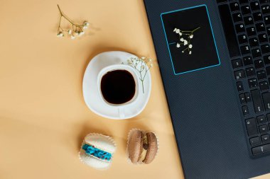 Düz uzanış, üst düzey ofis masası, dizüstü bilgisayarlı çalışma alanı, kahve fincanı ve çiçekli badem kurabiyesi, turuncu arka planda, evden çalışma, uzak çalışma