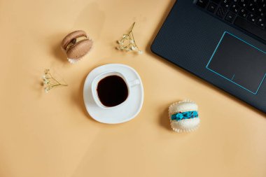 Düz uzanış, üst düzey ofis masası, dizüstü bilgisayarlı çalışma alanı, kahve fincanı ve çiçekli badem kurabiyesi, turuncu arka planda, evden çalışma, uzak çalışma