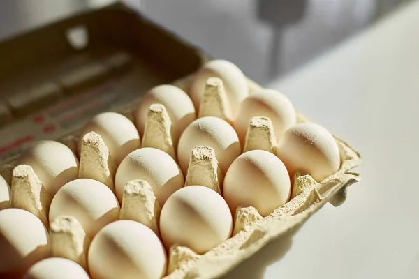 Cardboard  box with white eggs on white background, hard sunlight, Organic egg pack product.