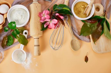 Çiçekli fırın ya da yemek çerçevesi, malzemeler, pastel turuncu arka planda hamur işi için mutfak malzemeleri, bahar pişirme teması. Üst görünüm, alanı kopyala.