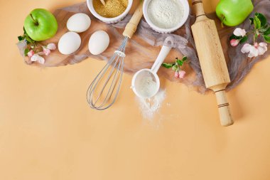 Pastane veya elmalı fırın çerçevesi, malzemeler, pastel turuncu arka planda hamur işi için mutfak malzemeleri, bahar pişirme teması. Üst görünüm, alanı kopyala.