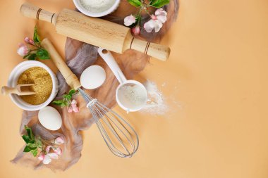 Çiçekli fırın ya da yemek çerçevesi, malzemeler, pastel turuncu arka planda hamur işi için mutfak malzemeleri, bahar pişirme teması. Üst görünüm, alanı kopyala.