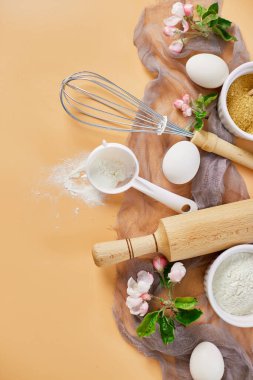 Çiçekli fırın ya da yemek çerçevesi, malzemeler, pastel turuncu arka planda hamur işi için mutfak malzemeleri, bahar pişirme teması. Üst görünüm, alanı kopyala.