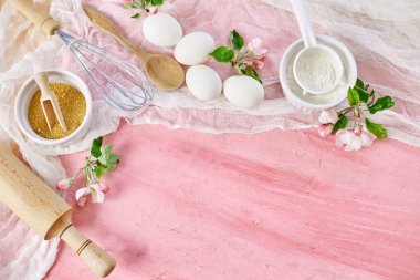 Çiçekli fırın veya yemek iskeleti, malzemeler, pembe arka planda hamur işi için mutfak malzemeleri, bahar pişirme teması. Üst görünüm, alanı kopyala.