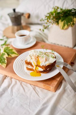 Breakfast on white bed sheets, good morning, toast with poached eggs, coffee, flowers, Hotel room early morning, honeymoon