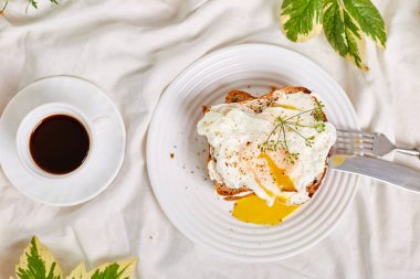 Top view Breakfast on white bed sheets, good morning, toast with poached eggs, coffee, flowers, Hotel room early morning, honeymoon