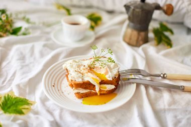 Breakfast on white bed sheets, good morning, toast with poached eggs, coffee, flowers, Hotel room early morning, honeymoon