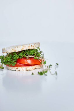 Çıtır pirinçli sağlıklı hamburger sebzeli domates ve beyaz arka planda mikroyeşiller, vegan beslenme, diyet yiyecekler.