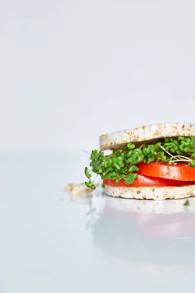 Healthy burger with crispy rice bread vegetables tomato and microgreens on white background, vegan nutrtional, diet food