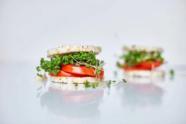 Healthy burger with crispy rice bread vegetables tomato and microgreens on white background, vegan nutrtional, diet food